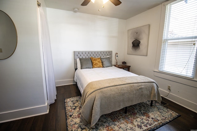 bedroom featuring dark wood-type flooring, multiple windows, a ceiling fan, and baseboards