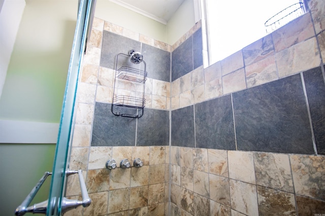 bathroom featuring ornamental molding and a tile shower