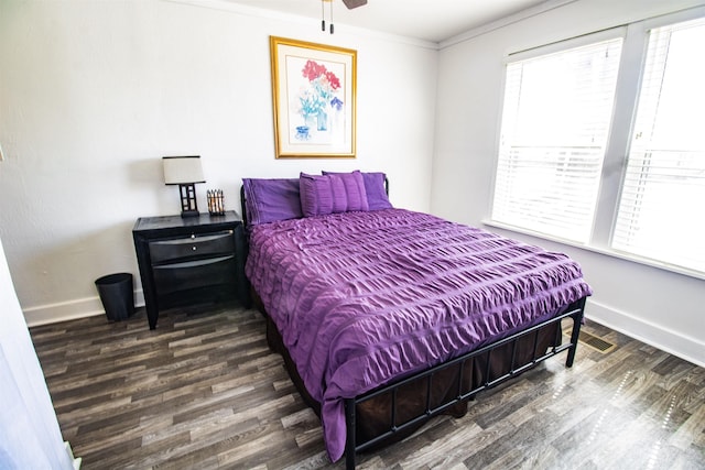 bedroom with crown molding, baseboards, and wood finished floors