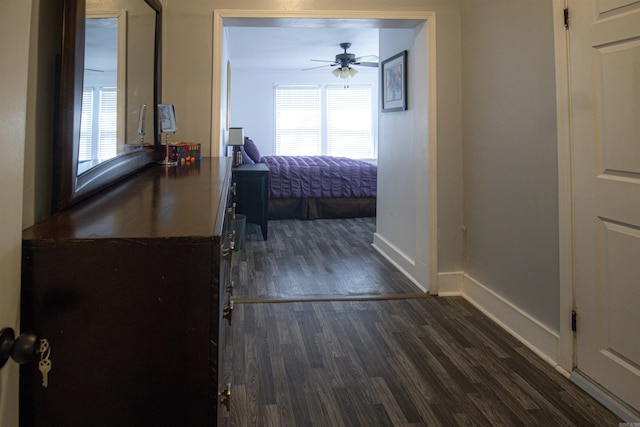 bedroom with ceiling fan, dark wood-type flooring, and baseboards