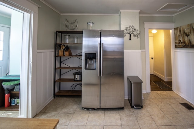 kitchen featuring visible vents, light tile patterned flooring, wainscoting, stainless steel fridge with ice dispenser, and crown molding