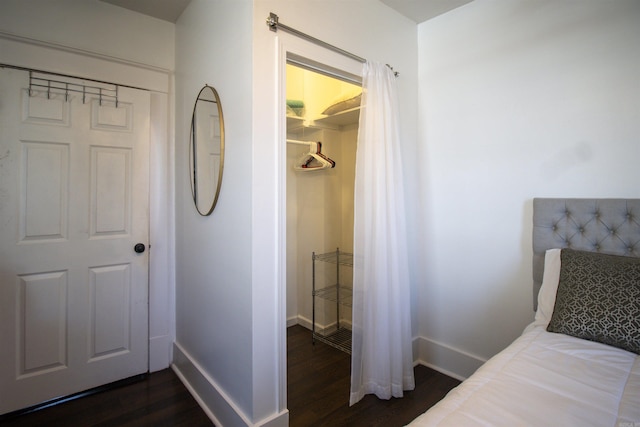 bedroom featuring a spacious closet, baseboards, dark wood-style flooring, and a closet