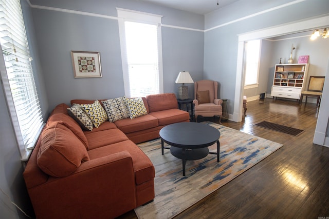 living area featuring baseboards, wood finished floors, and crown molding