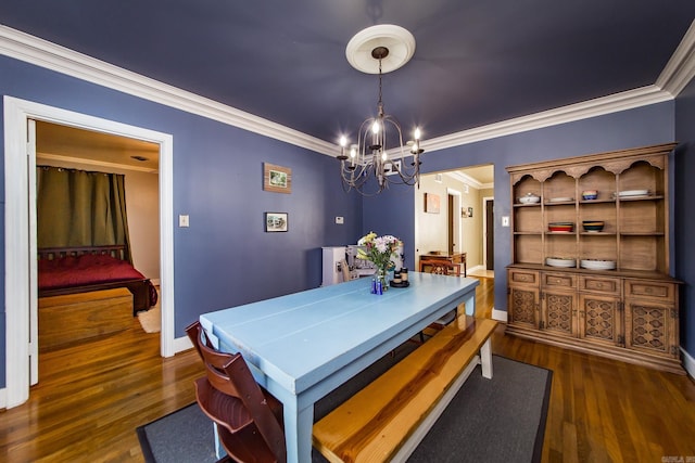 dining space with a chandelier, ornamental molding, baseboards, and wood finished floors