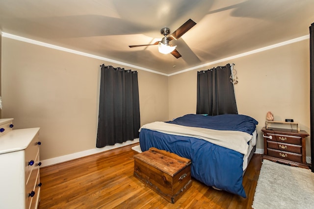 bedroom with crown molding, baseboards, and wood finished floors