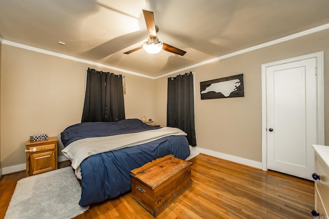 bedroom with baseboards, a ceiling fan, wood finished floors, and crown molding