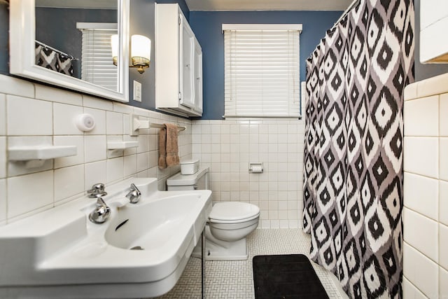 bathroom with tile patterned flooring, toilet, a shower with curtain, tile walls, and a sink