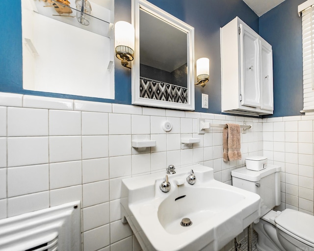 full bathroom featuring a sink, toilet, and wainscoting