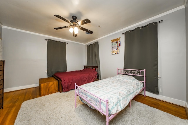 bedroom featuring ceiling fan, baseboards, wood finished floors, and ornamental molding