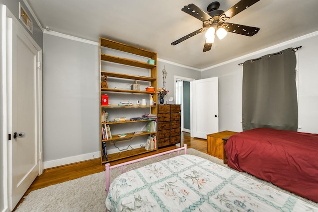 bedroom featuring baseboards, wood finished floors, ornamental molding, and a ceiling fan