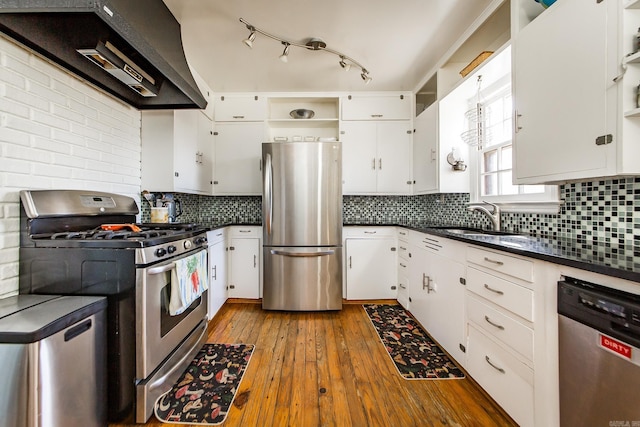 kitchen featuring open shelves, stainless steel appliances, dark countertops, and a sink