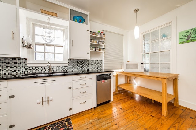 kitchen with open shelves, a sink, stainless steel dishwasher, dark countertops, and white microwave