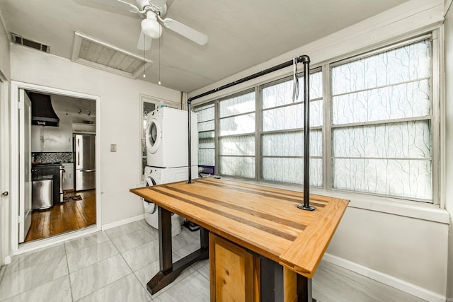 dining area with visible vents, baseboards, stacked washer / drying machine, and a ceiling fan