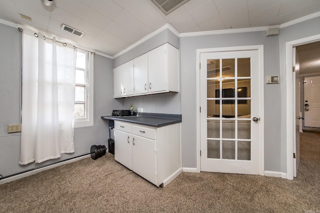 kitchen featuring visible vents, ornamental molding, dark countertops, white cabinets, and light colored carpet