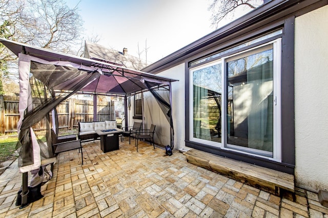 view of patio / terrace with a gazebo, an outdoor living space with a fire pit, and fence