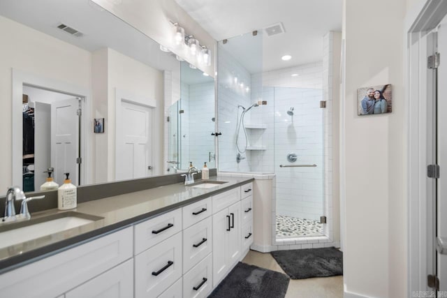 bathroom with double vanity, visible vents, a stall shower, and a sink