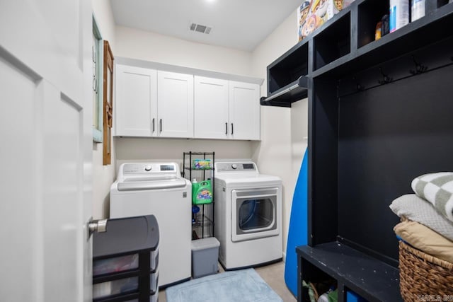 clothes washing area featuring cabinet space, visible vents, and washer and dryer