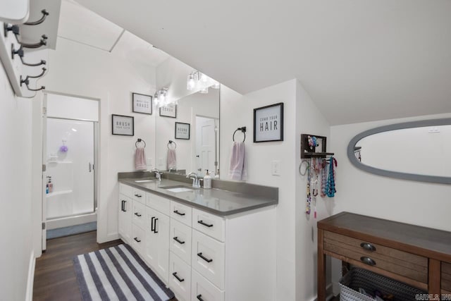 bathroom featuring a shower stall, wood finished floors, double vanity, and a sink