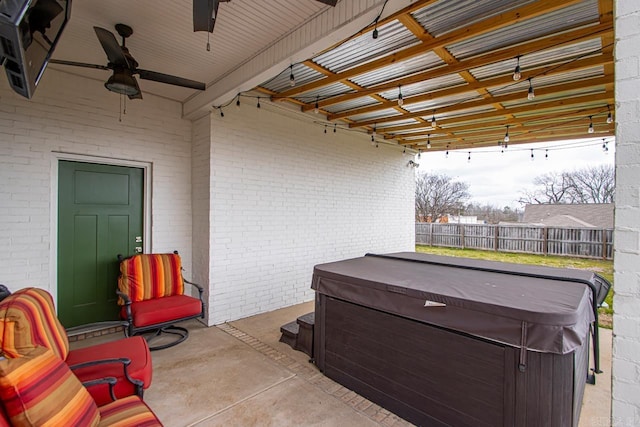 view of patio with a hot tub, ceiling fan, and fence