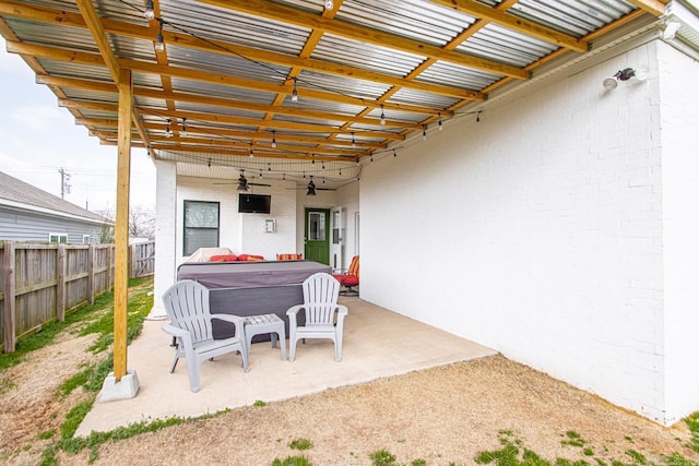 view of patio / terrace with a ceiling fan, fence, and a hot tub