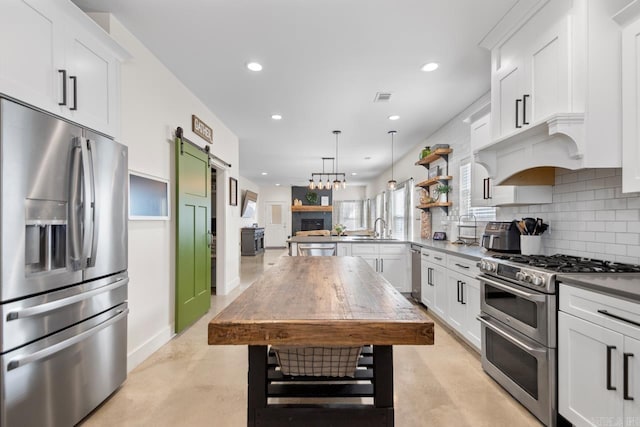 kitchen with visible vents, a sink, a barn door, appliances with stainless steel finishes, and decorative backsplash