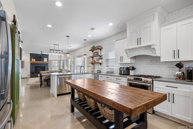 kitchen with visible vents, under cabinet range hood, a peninsula, stainless steel appliances, and a sink