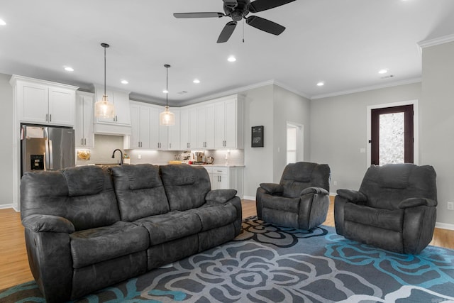 living room with ornamental molding, baseboards, light wood-type flooring, and ceiling fan