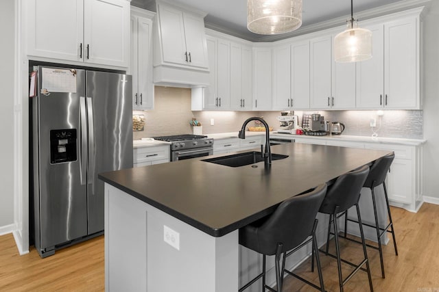 kitchen with light wood finished floors, appliances with stainless steel finishes, a breakfast bar, and a sink