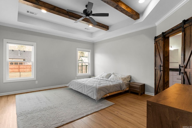 bedroom featuring visible vents, light wood-style flooring, baseboards, and a barn door