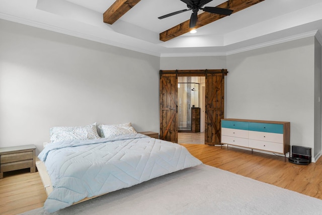 bedroom featuring beamed ceiling, a barn door, wood finished floors, a raised ceiling, and a ceiling fan