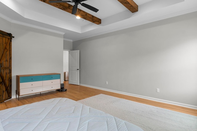 bedroom with beamed ceiling, ornamental molding, wood finished floors, a barn door, and baseboards