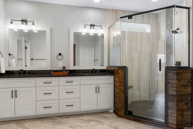 full bath with a sink, marble finish floor, a stall shower, and double vanity