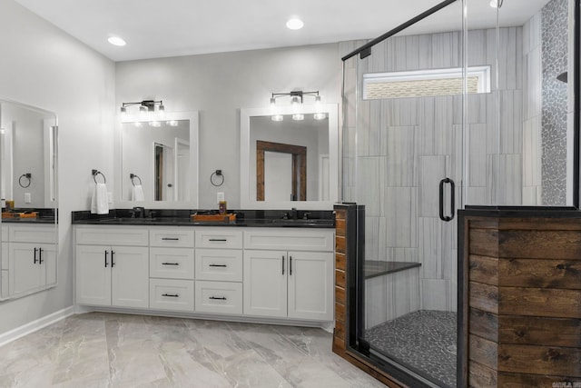 full bath featuring double vanity, a stall shower, marble finish floor, and a sink