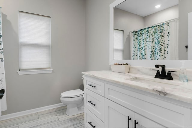 bathroom with vanity, toilet, baseboards, and a wealth of natural light