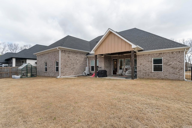 rear view of house with a patio area, brick siding, a lawn, and fence