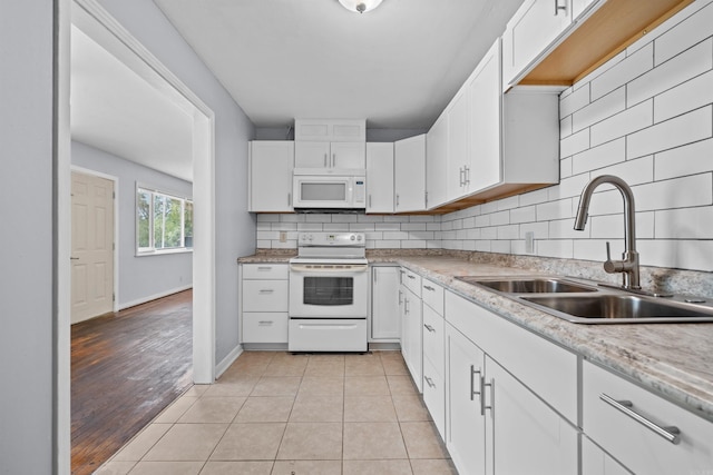 kitchen with light tile patterned floors, decorative backsplash, white appliances, white cabinetry, and a sink