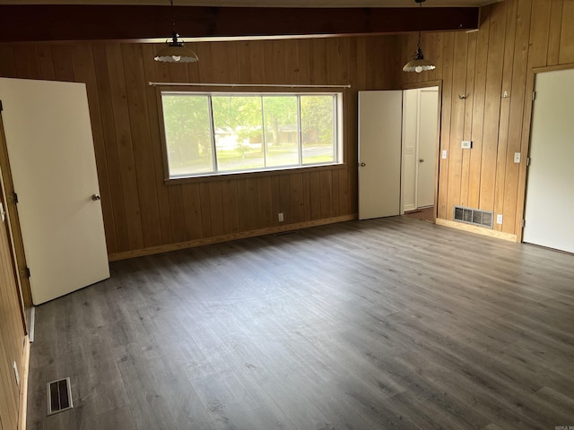 unfurnished room with visible vents, baseboards, wooden walls, and wood finished floors