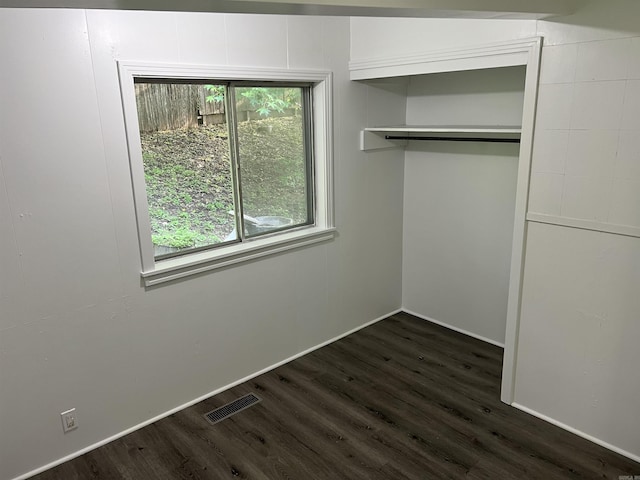 unfurnished bedroom featuring a closet, multiple windows, visible vents, and dark wood-style flooring