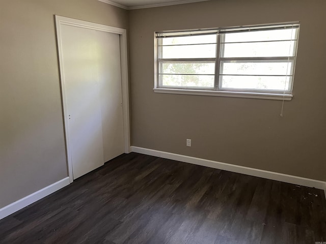 unfurnished bedroom featuring dark wood finished floors, baseboards, and a closet