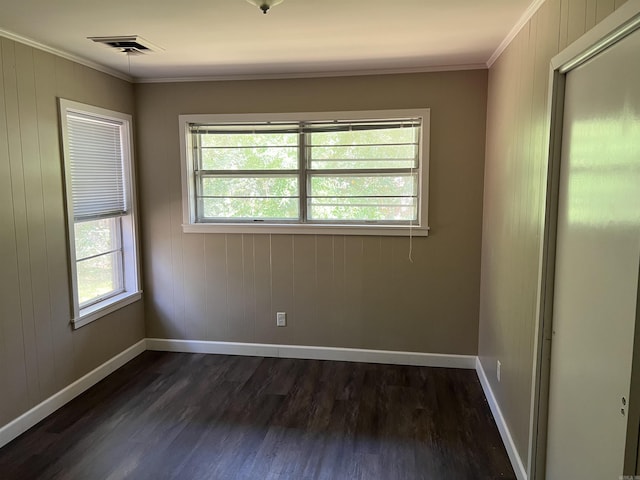 unfurnished room featuring dark wood-type flooring, crown molding, and visible vents