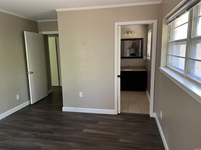 unfurnished bedroom featuring dark wood-style flooring, wet bar, baseboards, and ornamental molding