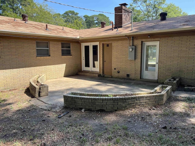 back of house with a patio area, brick siding, and a chimney