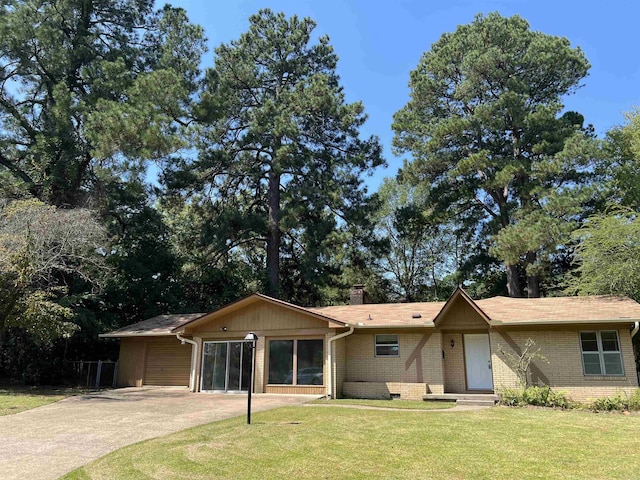 view of front facade with brick siding, a front lawn, concrete driveway, a chimney, and an attached garage