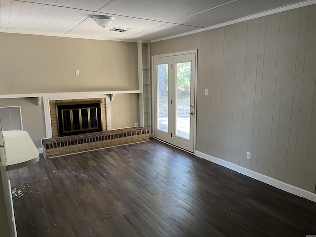 unfurnished living room with wood finished floors, visible vents, baseboards, a fireplace, and ornamental molding