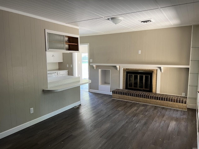 unfurnished living room with visible vents, baseboards, a brick fireplace, and dark wood-style floors