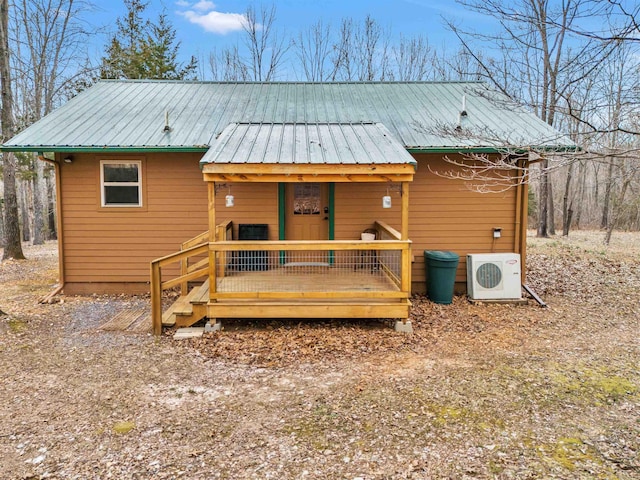 back of house with covered porch, metal roof, and ac unit