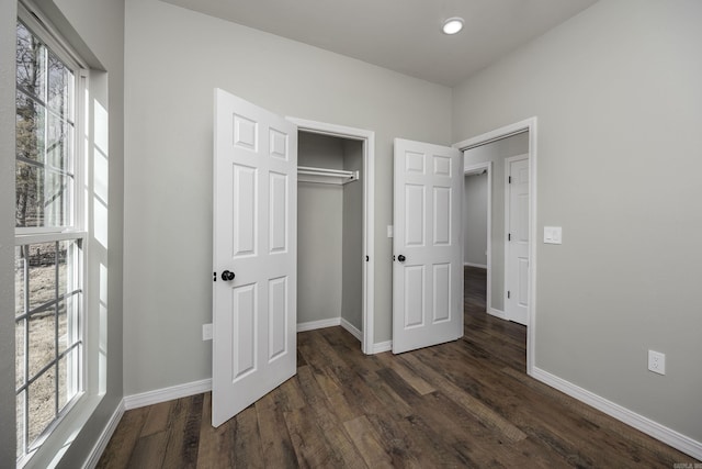 unfurnished bedroom with dark wood-type flooring, baseboards, and a closet