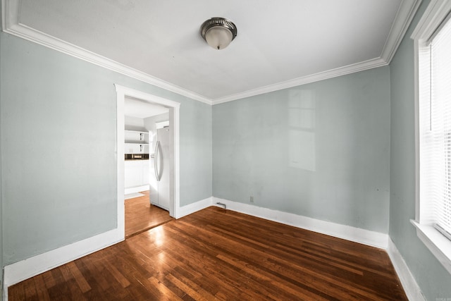 empty room with crown molding, baseboards, and wood finished floors