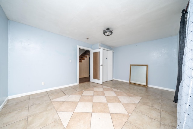 spare room featuring light tile patterned flooring and baseboards