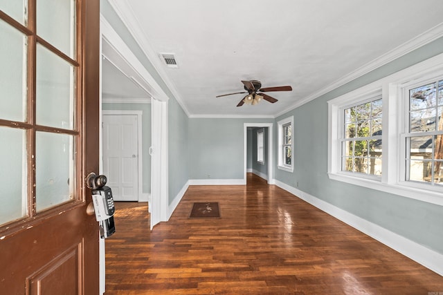 empty room with wood finished floors, a ceiling fan, visible vents, baseboards, and crown molding